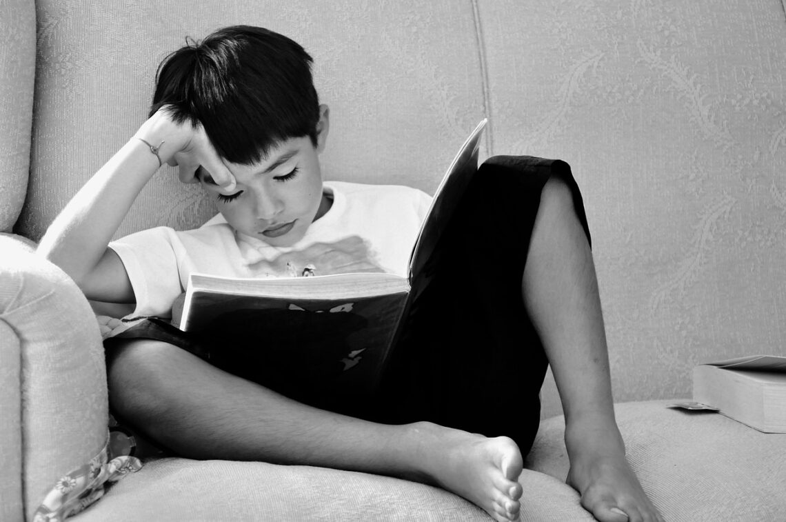 Black and white photo of a young child enjoying a book.