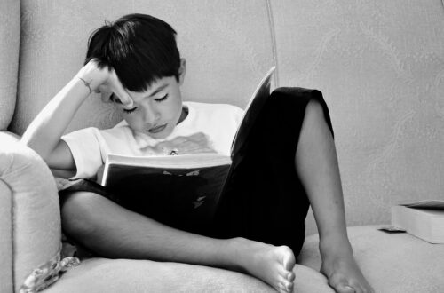 Black and white photo of a young child enjoying a book.